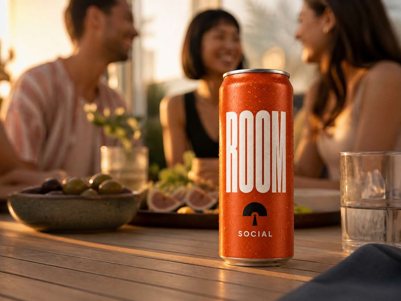 ROOM Social can on a table while friends gather for food and conversation